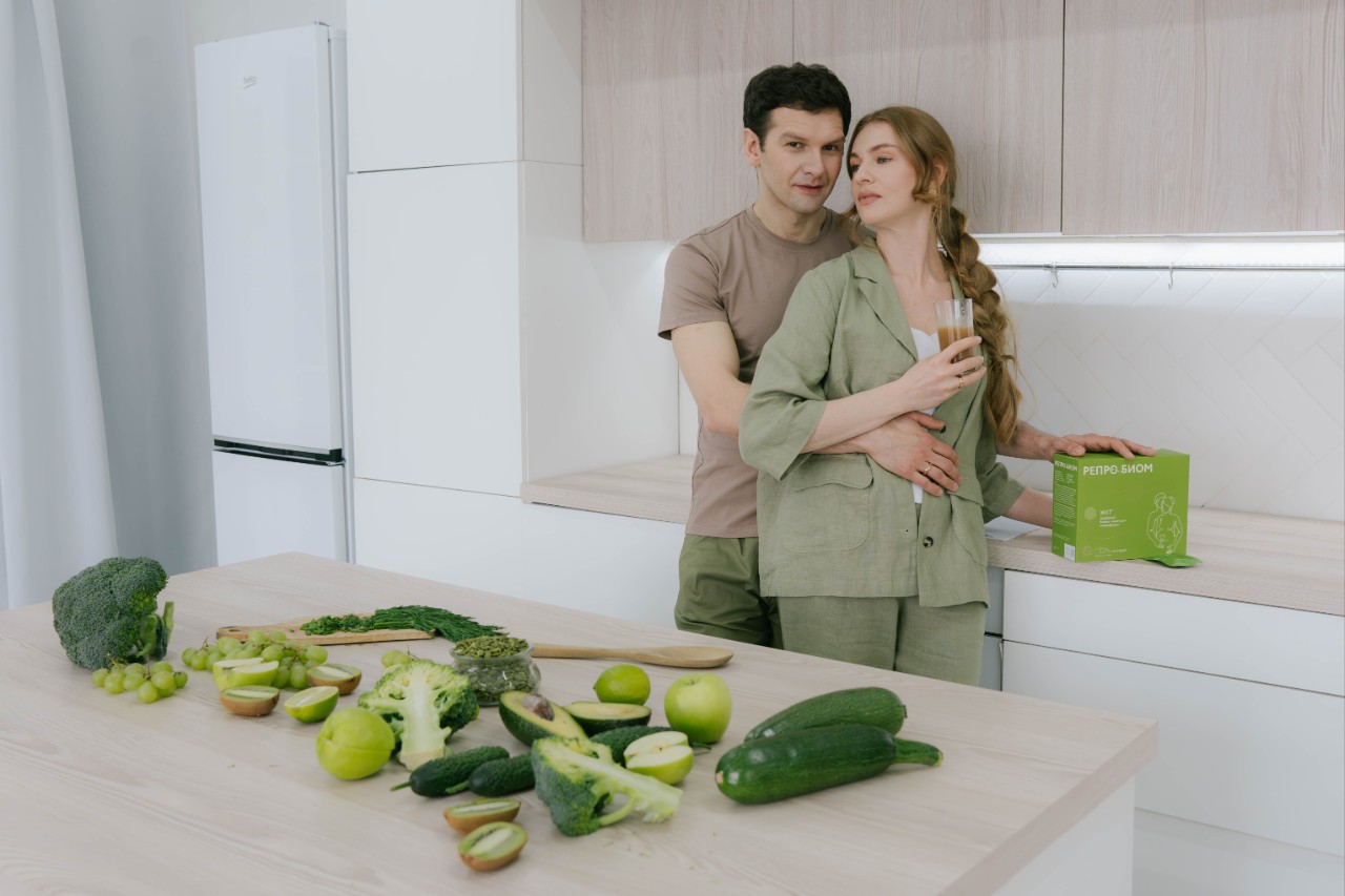 Пара в кухне с овощами и напитком, обсуждают здоровье и репродуктивное благополучие.